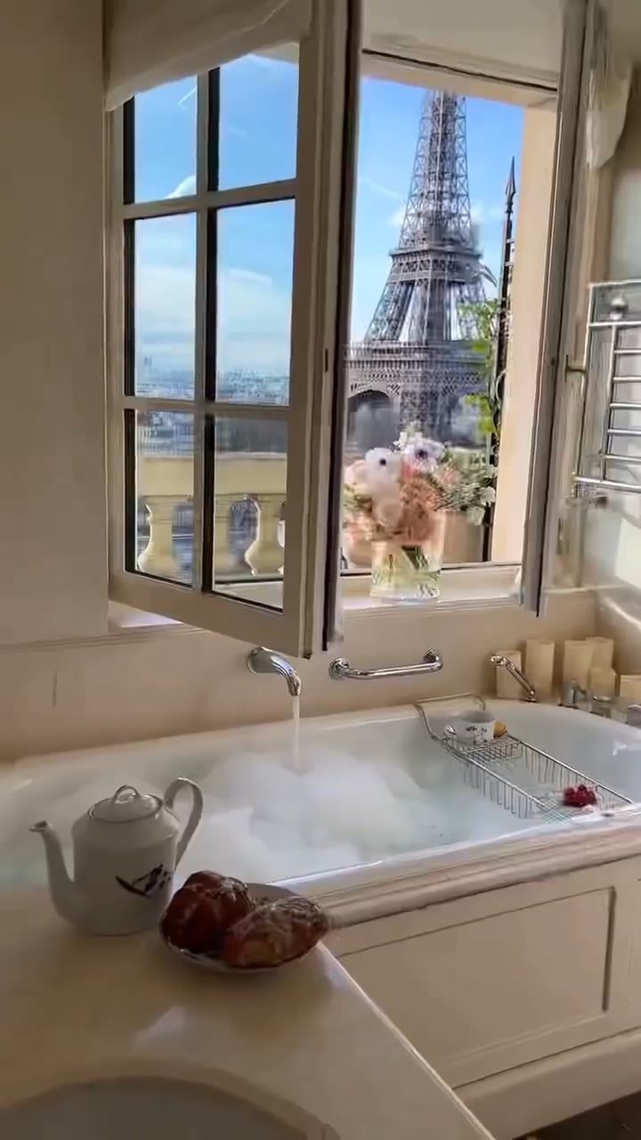 a bath tub sitting next to a window with the eiffel tower in the background