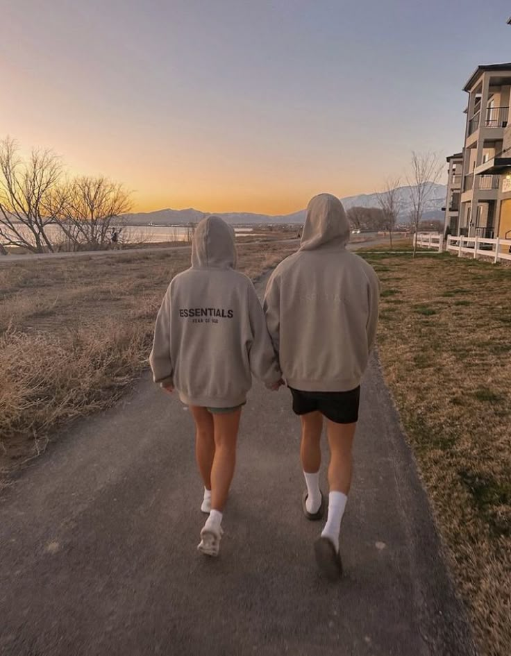 two people walking down a road with their back to the camera