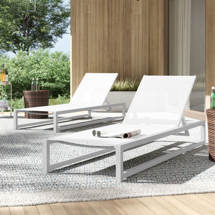 two lounge chairs sitting on top of a wooden floor next to a table and chair