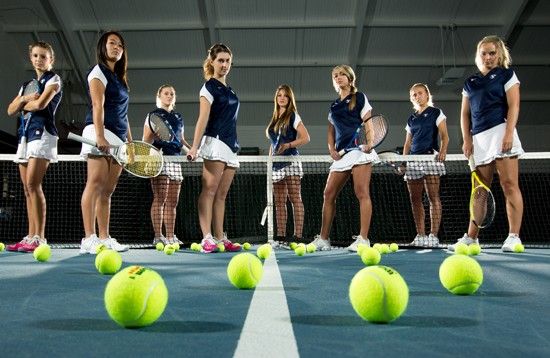 a group of people standing on top of a tennis court holding racquets