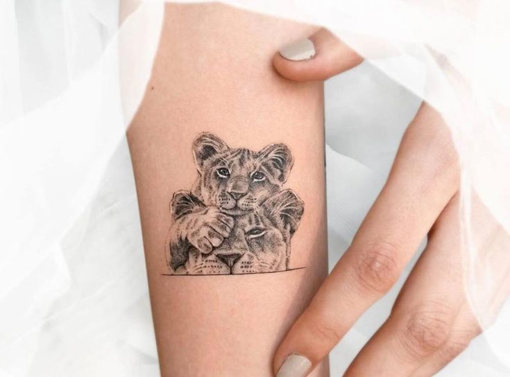 a woman's arm with a small tattoo of two lions on the left side