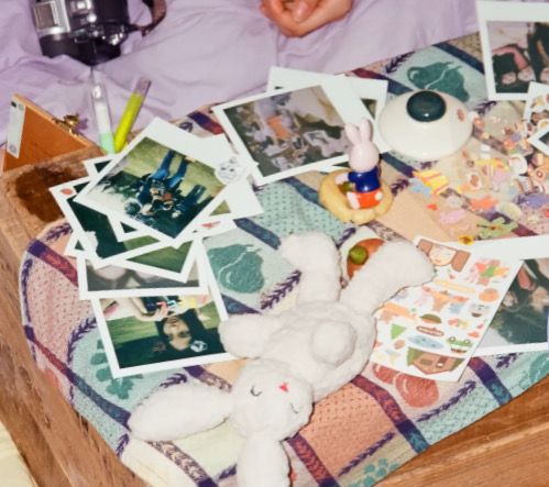 a bed topped with lots of pictures and stuffed animals next to a person laying down