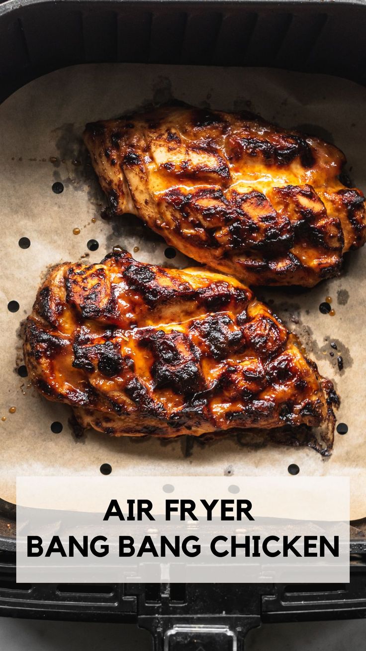 two pieces of grilled chicken sitting in an air fryer with the words, air fryer bang bang chicken