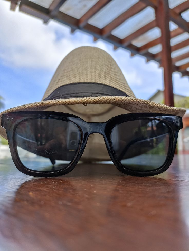 a hat and sunglasses sitting on top of a wooden table