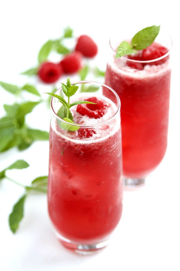 two glasses filled with raspberry mojitas and garnished with mint