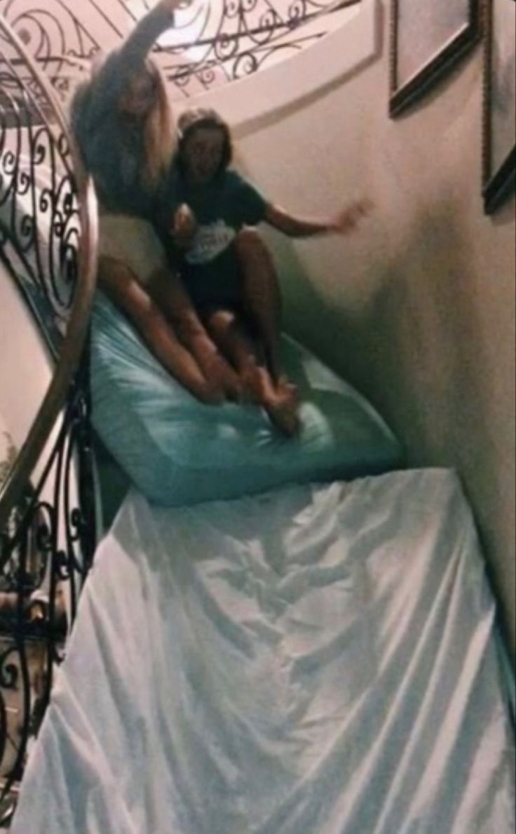 a woman and child are sitting on a bed in a spiral stair case that is decorated with wrought iron railings