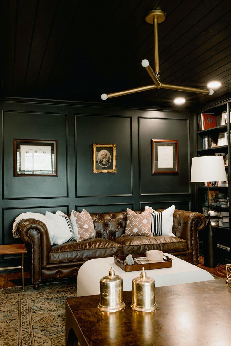 a living room with leather couches and bookshelves on the wall behind them