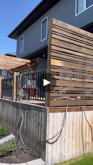 a wooden fence next to a house with an electrical outlet on the side of it