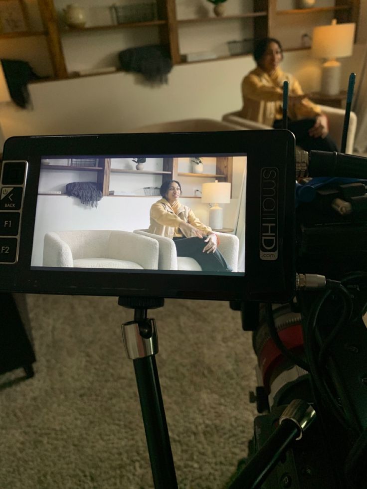 a video camera recording a woman sitting on a couch