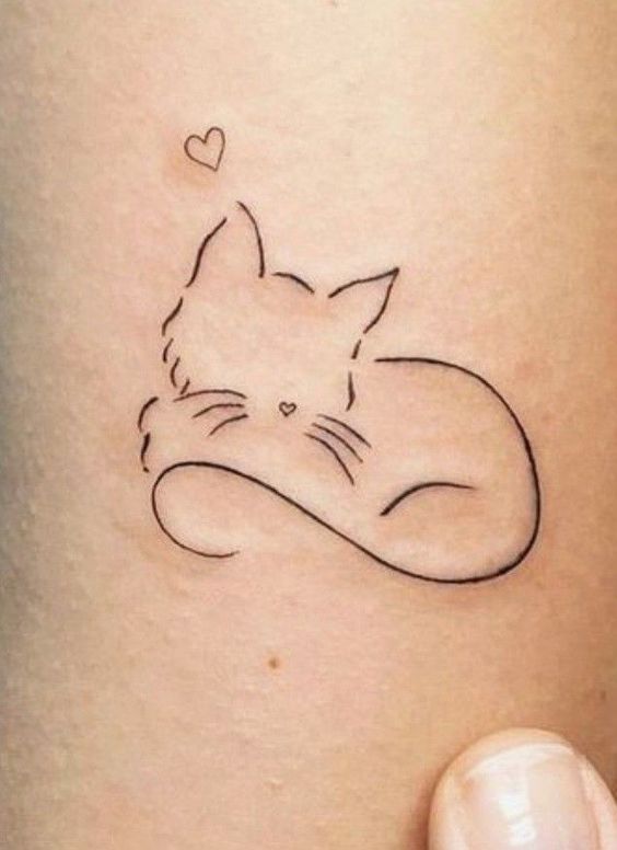 a cat tattoo with a heart on it's back side, sitting next to a woman's leg