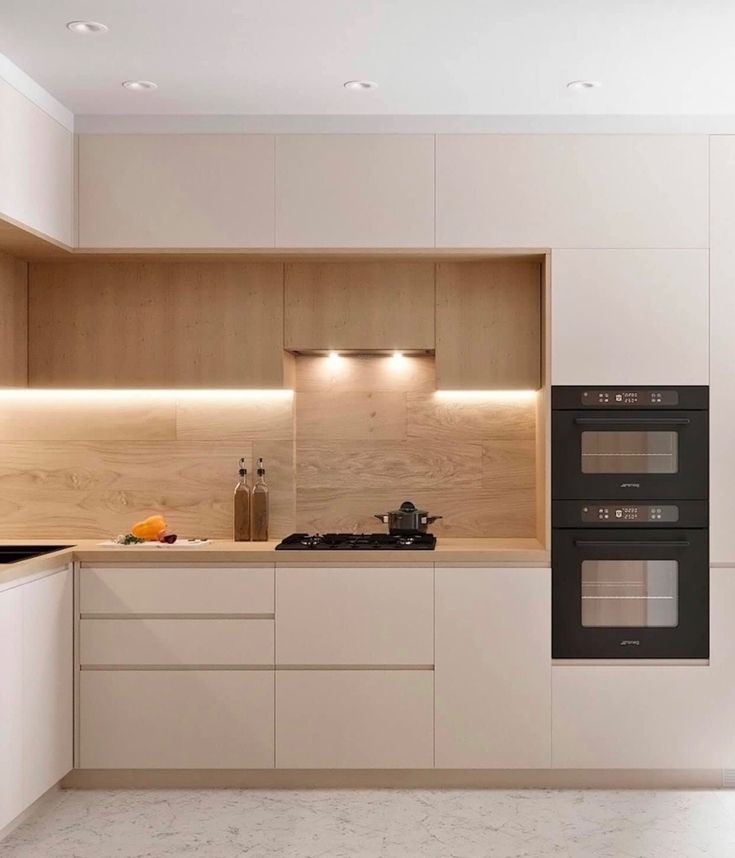 an empty kitchen with two ovens and a sink in the middle is illuminated by recessed lighting