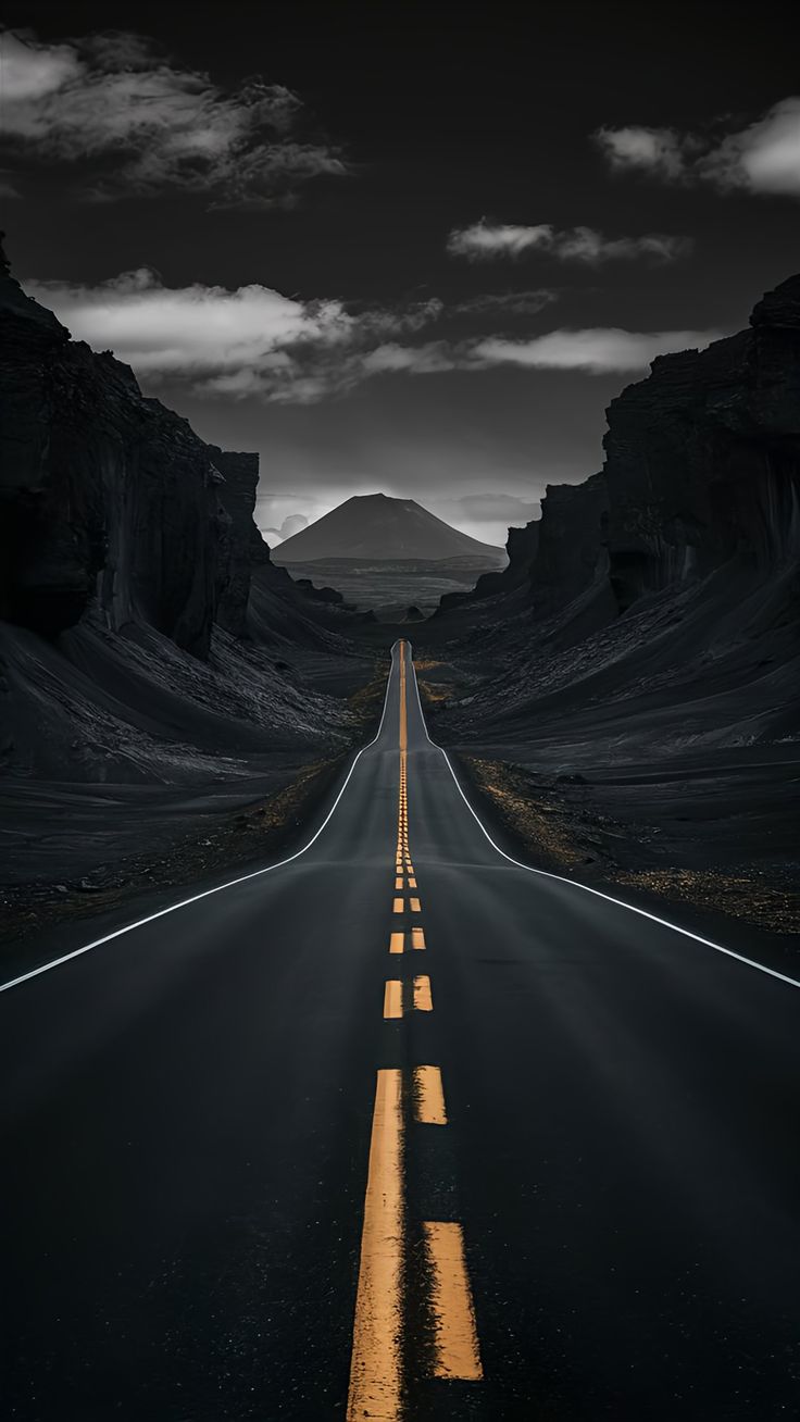 an empty road in the middle of nowhere with no cars on it and mountains in the background