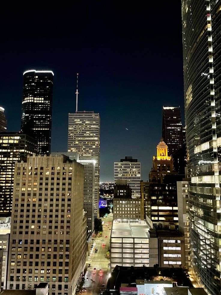 the city skyline is lit up at night, with skyscrapers in the foreground