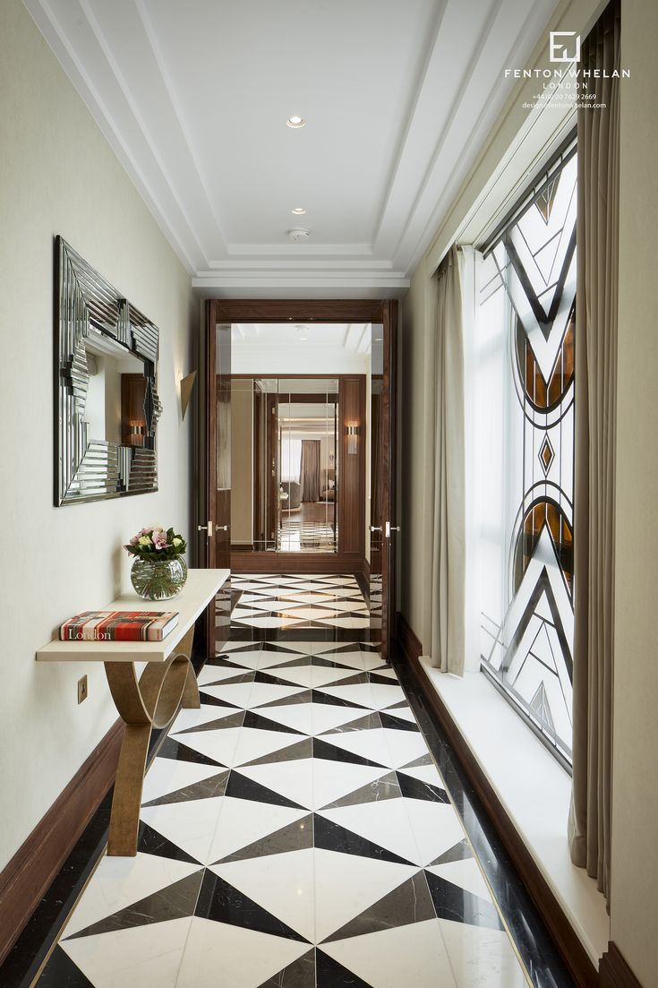 a hallway with black and white flooring, large windows and a mirror on the wall