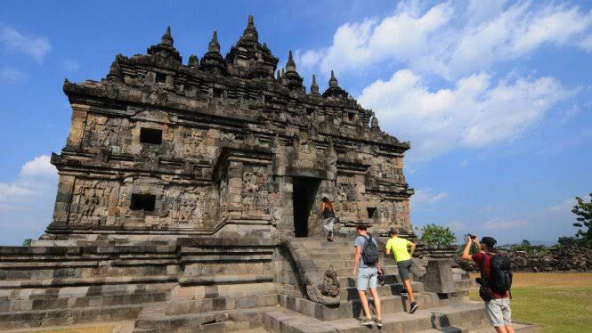 people walking up and down steps in front of a stone structure with carvings on it