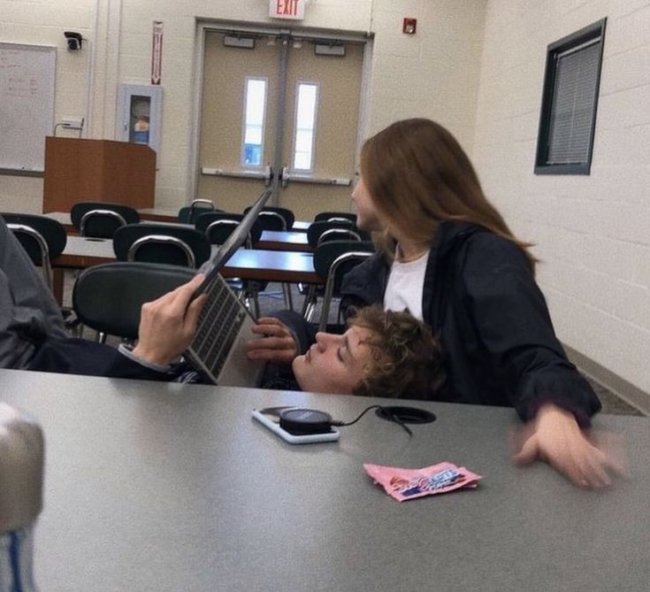 two people sitting at a table with laptops