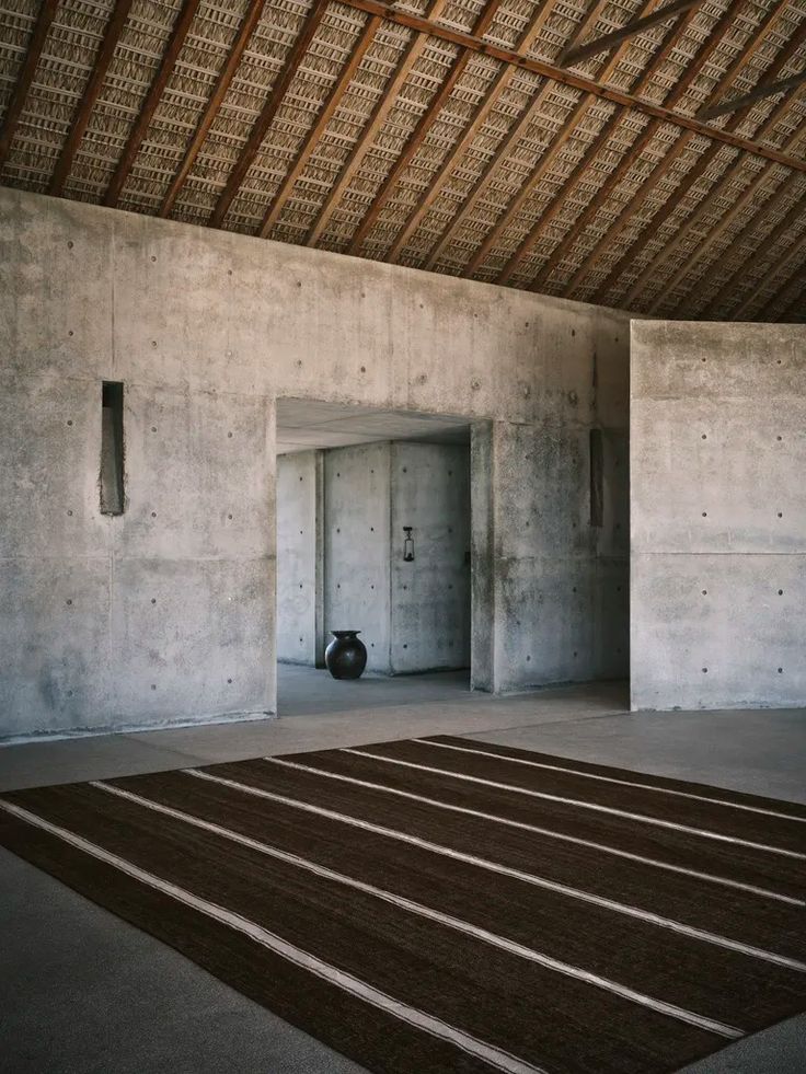 an empty room with concrete walls and a rug on the floor in front of it