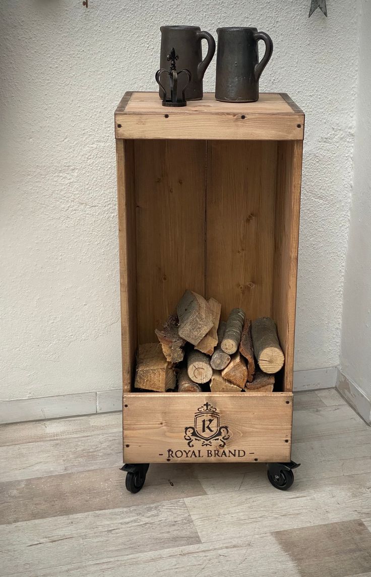 a wooden crate filled with logs and two mugs