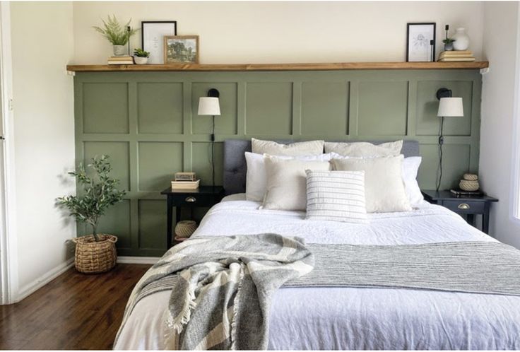 a bed with white sheets and pillows in a bedroom next to a wooden headboard