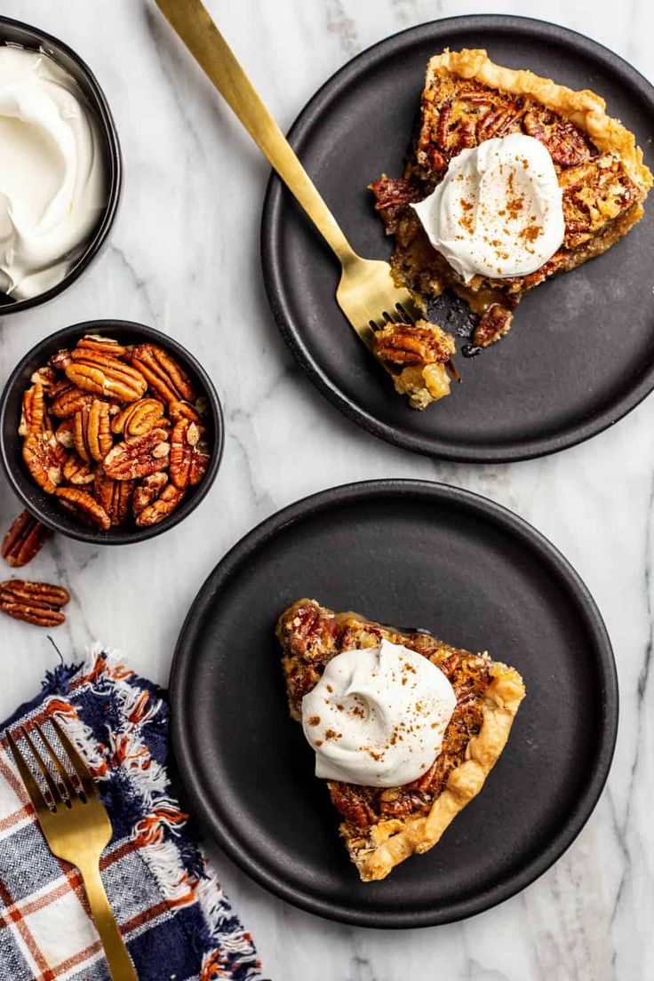 two black plates topped with pecan pie and whipped cream next to bowls of pecans