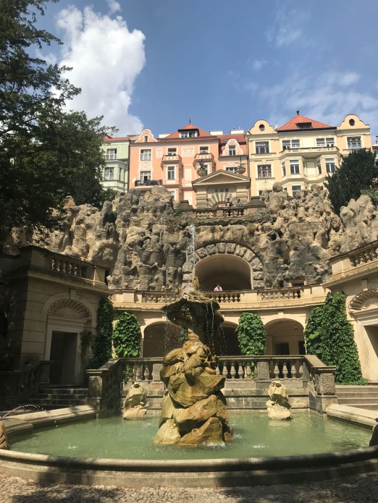 a fountain in front of a building with many windows and balconies on the side