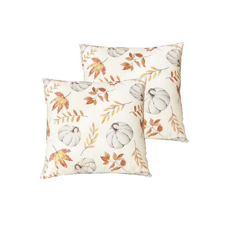 two decorative pillows with leaves and acorns on them, one is white and the other is orange