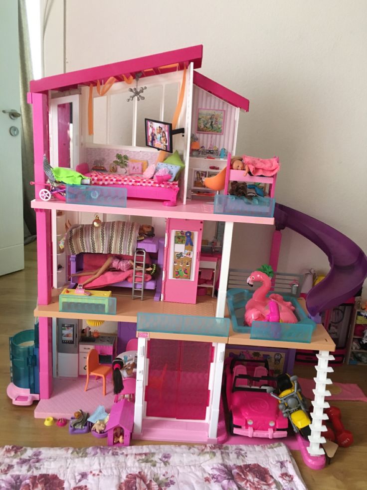 a pink doll house with lots of furniture and accessories on the floor next to a rug