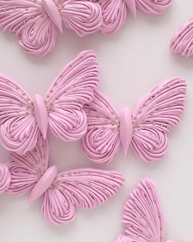 some pink butterflies are on a white surface and one is made out of fondant