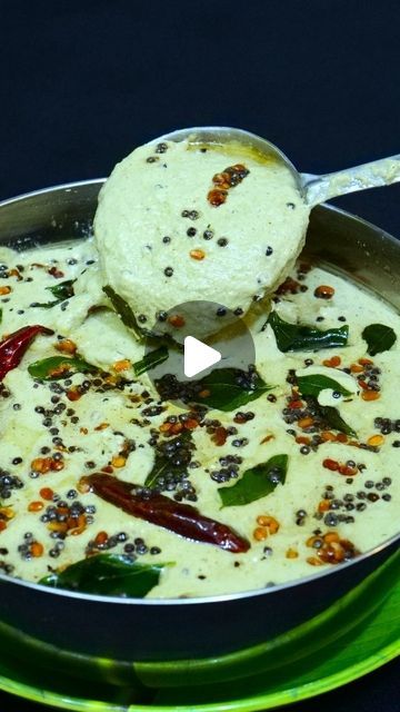 a pan filled with food on top of a green plate and a spoon in it