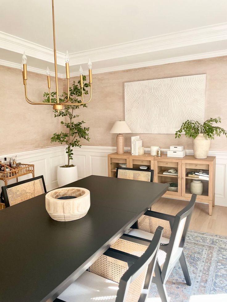 a dining room table with chairs and a potted plant