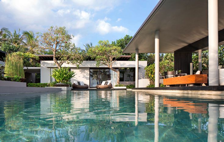 an outdoor swimming pool with lounge chairs and trees in the backgroung area