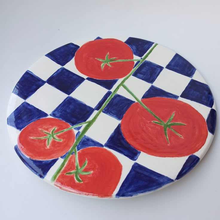 a blue and white checkered plate with tomatoes painted on the side, sitting on a table