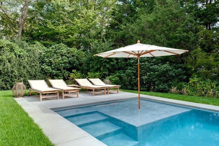 an empty swimming pool with lounge chairs and umbrella