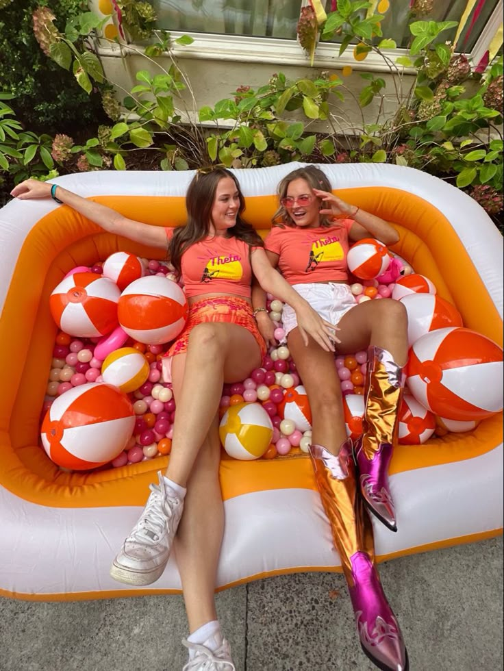 two women sitting on an inflatable float with balls