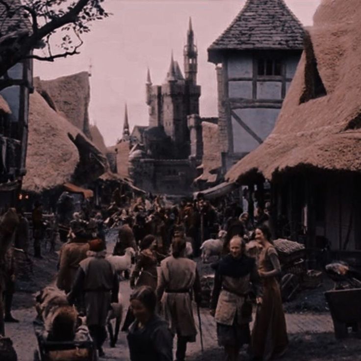 a group of people walking down a street next to tall buildings with thatched roofs