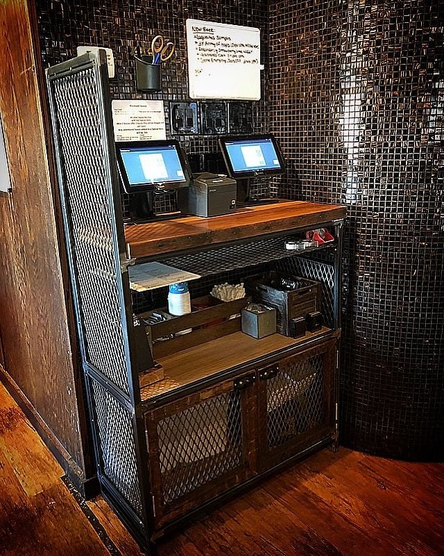 a desk with two computers on top of it in front of a wall that has mosaic tiles