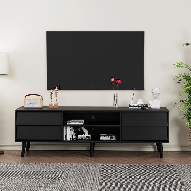 a living room with a black entertainment center and potted plants on the sideboard