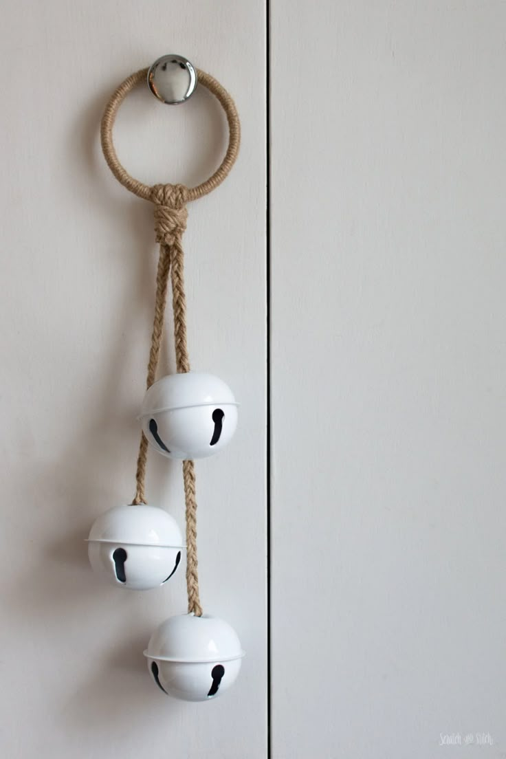 three white lights hanging from a rope on a wall next to a door with an object in the middle