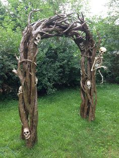 an archway made out of branches with skeletons in the grass and trees around it,