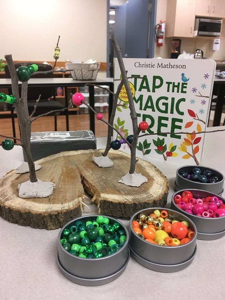 four tins filled with different colored beads on top of a white table next to a sign that says tap the magic tree