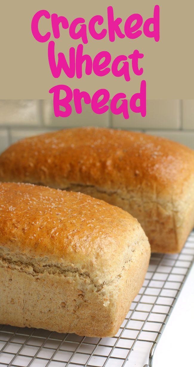 two loaves of bread sitting on top of a cooling rack with the words cracked wheat bread