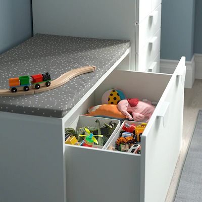 a toy train sits in the drawer of a child's storage unit with toys