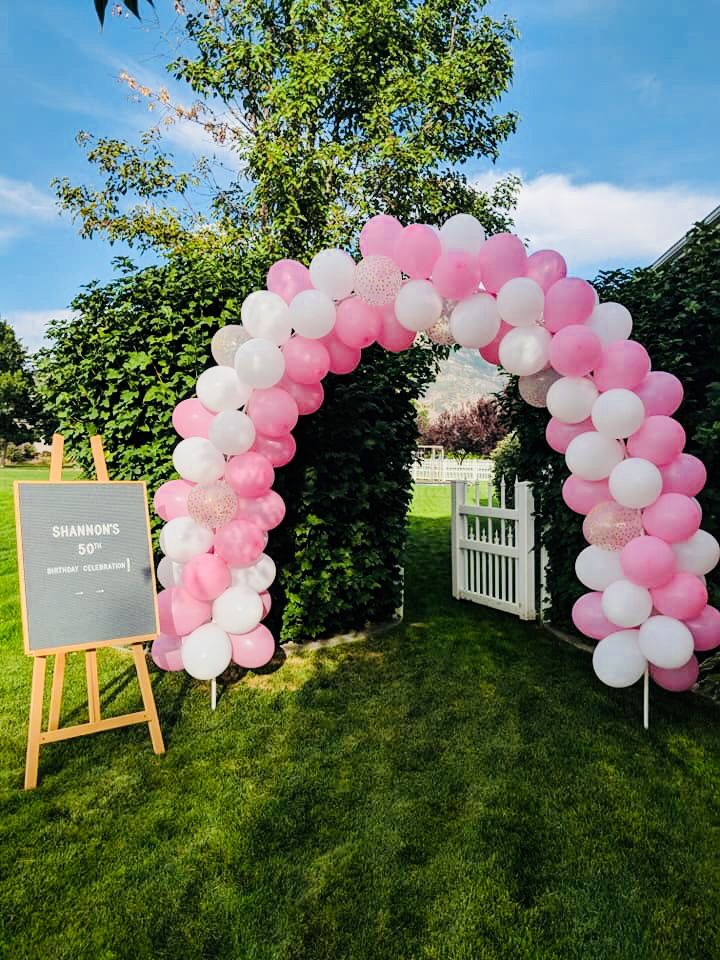 a pink and white arch with balloons in the shape of a heart is on display