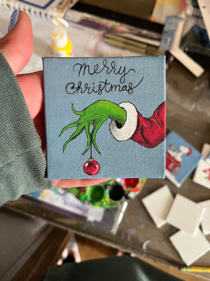 a hand holding up a christmas card with the words merry christmas on it and an elf's hat