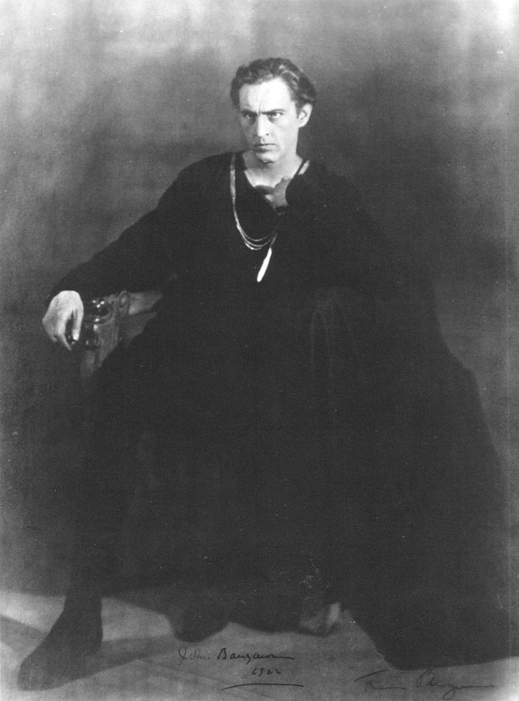 an old photo of a man in black sitting down