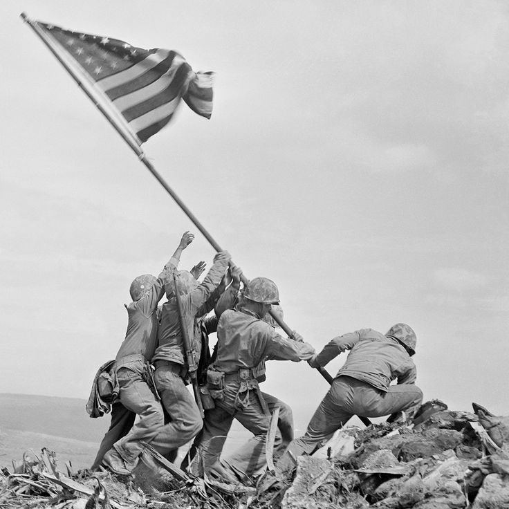 soldiers raising the flag on top of a hill