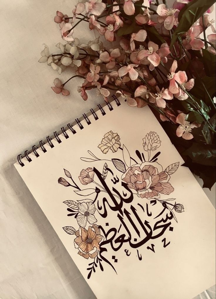 a notebook with arabic writing on it next to some flowers