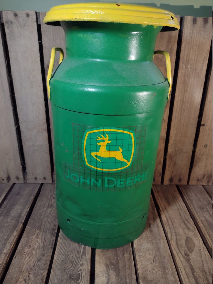 a green and yellow plastic container sitting on top of a wooden floor next to a fence