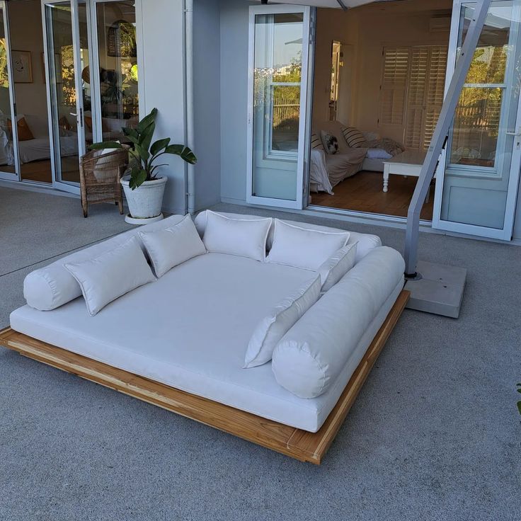 a large white bed sitting on top of a wooden platform in front of a house