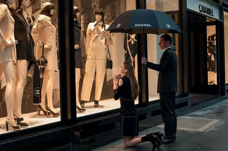 a woman standing next to a man holding an umbrella in front of mannequins